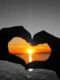 Manos formando corazón con el sol en el centro
